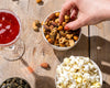 Nori Bar Nuts by Eleven Madison Home on a bar with popcorn and a cocktail, maker photo