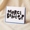 Merci Beaucoup letterpress greeting card by Dahlia Press standing on a natural cotton backdrop