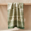 Vignoble tea towel hanging in soft folds over an oak shelf edge
