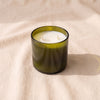 The Field Candle in Heirloom + Argan, 13.5 oz soy blend candle in moss green glass