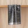 A Vol d'Oiseau Paris jacquard tea towel draped over an oak edge, showing how the cloth hangs