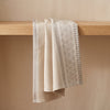 Dune Rayures jacquard tea towel draped over an oak edge, showing how the cloth hangs
