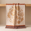 Thanksgiving jacquard tea towel draped over an oak edge, showing how the cloth hangs