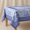 Promenade Impériale jacquard tablecloth in Lapis spread over a plain oak table, showing the fall and the woven border