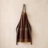 Barista bib apron in Moccacino hung on a wooden peg against the MA VIE cotton backdrop