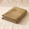 Hôtel Particulier linen tablecloth folded into a crisp block, the slubby linen weave and stacked edges visible