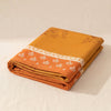Manor Lane tablecloth folded into a deep block on the MA VIE cotton, showing the stacked layers and the woven border