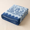 Promenade Impériale tablecloth in Lapis folded into a deep block, showing the stacked layers and the pavilion cartouche