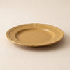 Dijon yellow stoneware dessert plate at a low angle, showing its moulded edge and profile