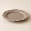 Lavender stoneware dessert plate at a low angle, showing its moulded edge and profile