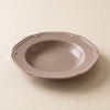 Lavender stoneware soup plate at a low angle, showing its broad rim and shallow well