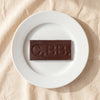 Casa Bosques sea salt dark chocolate bar unwrapped on a white plate