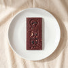 Casa Bosques toasted sesame and cacao sprinkle dark chocolate bar unwrapped on a white plate