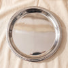 Orlando stainless steel round tray with beaded edge seen from above on MA VIE cotton