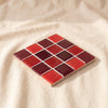 Glass tile coaster in Mon Amour, sixteen tiles in four reds, by Subtle Art Studios