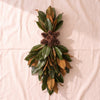 Fresh Magnolia Vertical Swag, 39 inch, hand tied by Weston Farms with pine cones at the waist, on a natural cotton backdrop