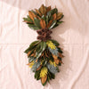 Fresh Magnolia Vertical Swag in High Point Tapestry, 39 inch, with blue and yellow conifer and pine cones at the waist, on a natural cotton backdrop
