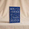 Bon Voyage travel journal by Printworks standing on a natural cotton backdrop