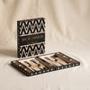 Lacquered backgammon set in black by Printworks open with packaging behind on a natural cotton backdrop