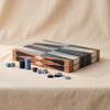 Lacquered backgammon set in blue by Printworks closed with pieces beside it on a natural cotton backdrop