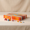 Lacquered backgammon set in red by Printworks closed with pieces beside it on a natural cotton backdrop