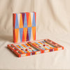 Lacquered backgammon set in red by Printworks open with packaging behind on a natural cotton backdrop
