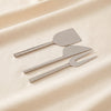 Modern cheese knives set by Zodax on a natural cotton backdrop